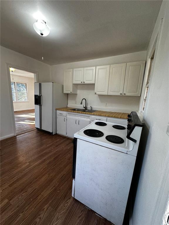 kitchen featuring a sink, white appliances, white cabinets, and dark wood-style flooring