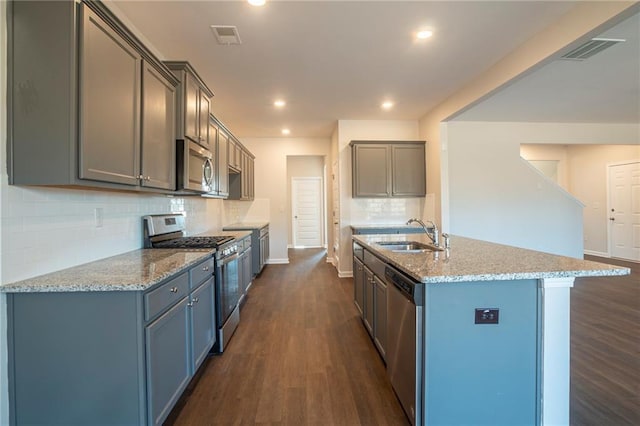 kitchen with a kitchen island with sink, sink, dark hardwood / wood-style flooring, and appliances with stainless steel finishes