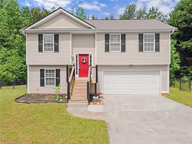 bi-level home featuring fence, an attached garage, concrete driveway, and a front yard