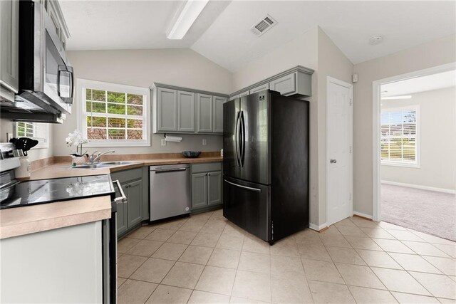 kitchen with visible vents, appliances with stainless steel finishes, gray cabinetry, a sink, and lofted ceiling
