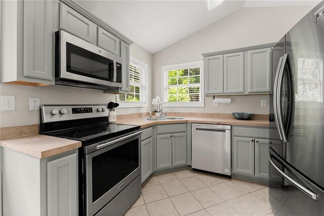 kitchen featuring light countertops, appliances with stainless steel finishes, vaulted ceiling, and gray cabinetry