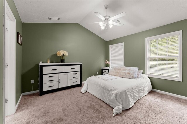 bedroom featuring baseboards, light colored carpet, lofted ceiling, and visible vents