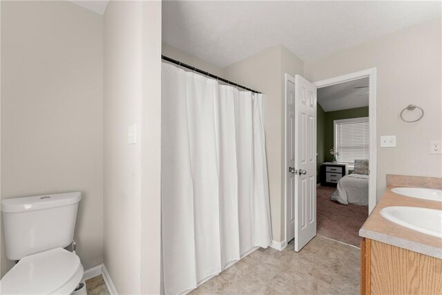 bathroom with double vanity, toilet, a sink, and a shower with curtain