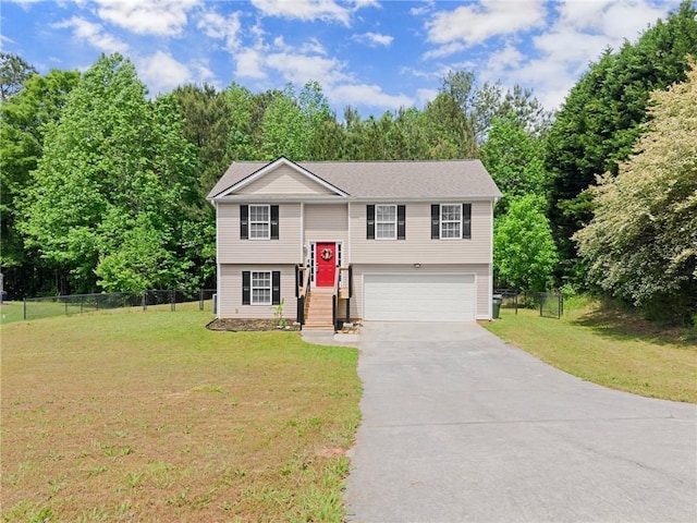 raised ranch featuring concrete driveway, an attached garage, fence, and a front lawn
