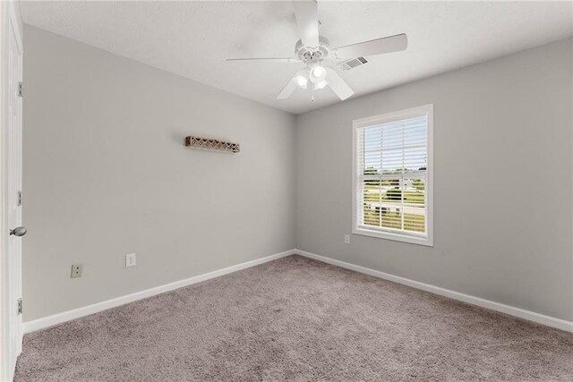 carpeted spare room with a ceiling fan, baseboards, and visible vents