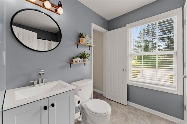 bathroom with toilet, baseboards, and vanity