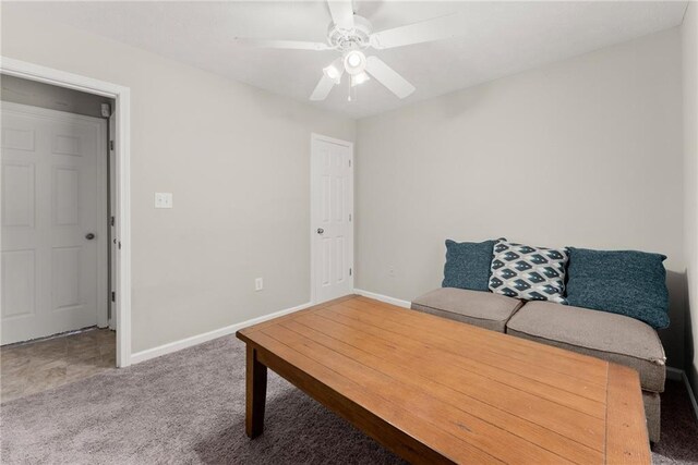 carpeted living room with baseboards and a ceiling fan