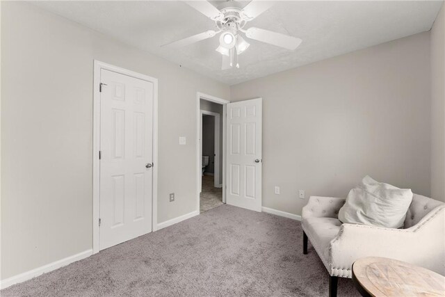 living area with carpet floors, ceiling fan, and baseboards