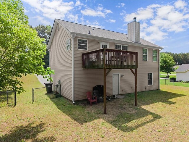 rear view of property featuring fence, a chimney, a yard, and a deck