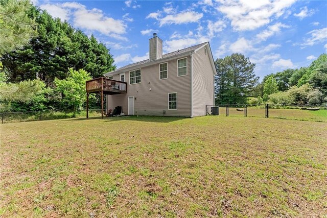 rear view of property featuring fence, central AC, a wooden deck, a chimney, and a yard