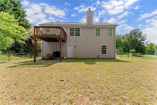 back of house featuring a fenced backyard, a chimney, a yard, and a deck