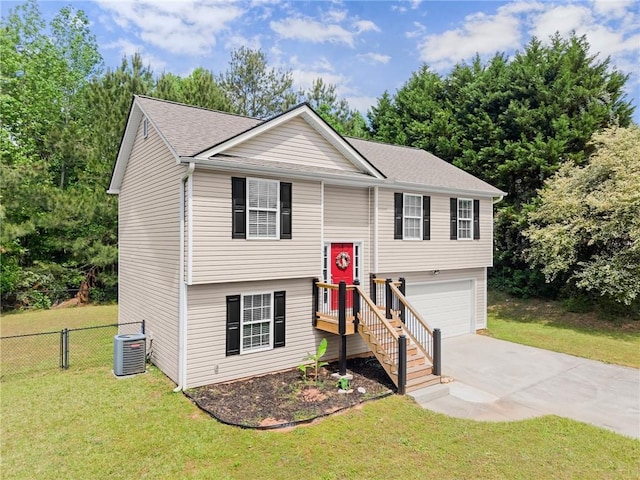 raised ranch with a garage, fence, cooling unit, a front lawn, and concrete driveway