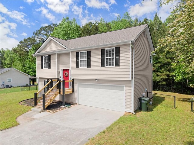 split foyer home with fence, an attached garage, concrete driveway, and a front yard