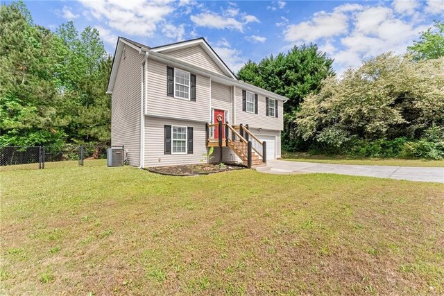 bi-level home featuring fence, an attached garage, central AC, a front yard, and concrete driveway