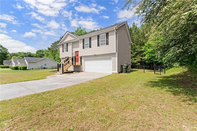 raised ranch with a garage, a front yard, and concrete driveway