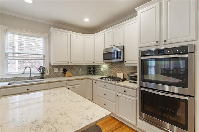 4404 Old Georgetown Trl, Atlanta, GA 30338 - kitchen featuring stainless steel appliances, a sink, white cabinets, backsplash, and crown molding