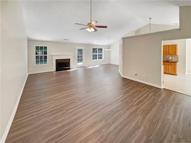 unfurnished living room featuring ceiling fan, a high end fireplace, dark hardwood / wood-style flooring, and vaulted ceiling