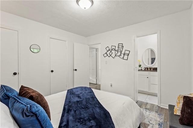 4781 Brownsville Rd, Powder Springs, GA 30127 - bedroom featuring wood finished floors, ensuite bath, and a textured ceiling