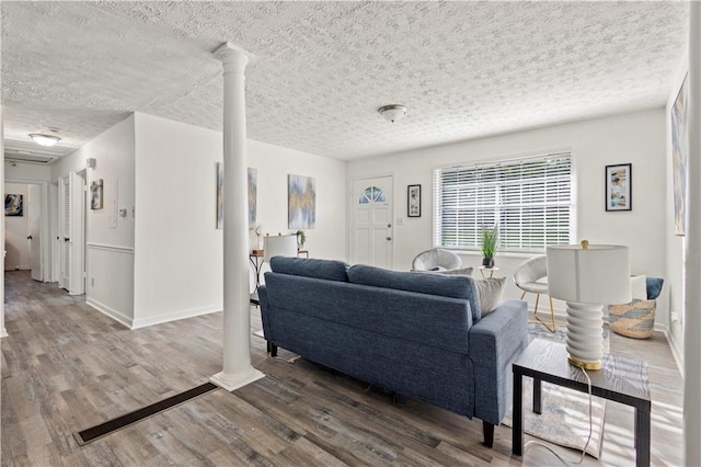 4781 Brownsville Rd, Powder Springs, GA 30127 - living area featuring ornate columns, wood finished floors, a textured ceiling, and baseboards