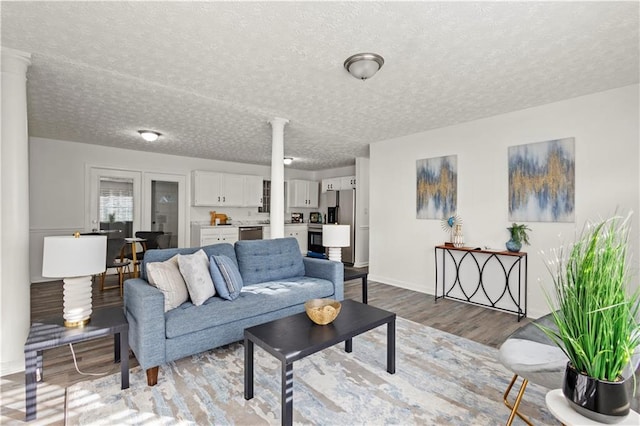 4781 Brownsville Rd, Powder Springs, GA 30127 - living area with ornate columns, light wood-type flooring, a textured ceiling, and baseboards