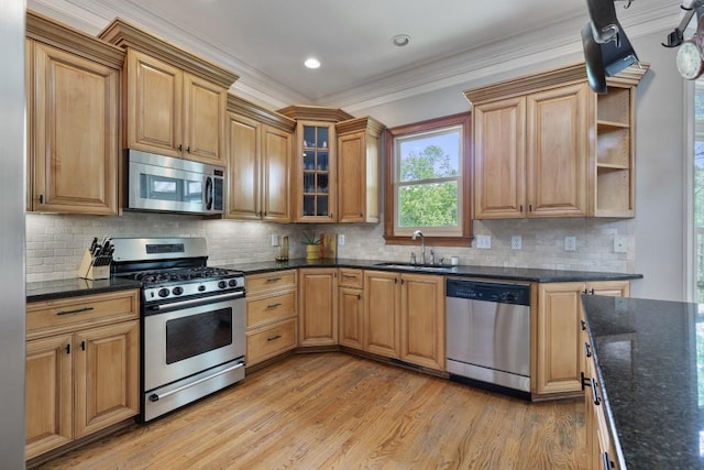 kitchen with backsplash, crown molding, a sink, stainless steel appliances, and light wood-style flooring