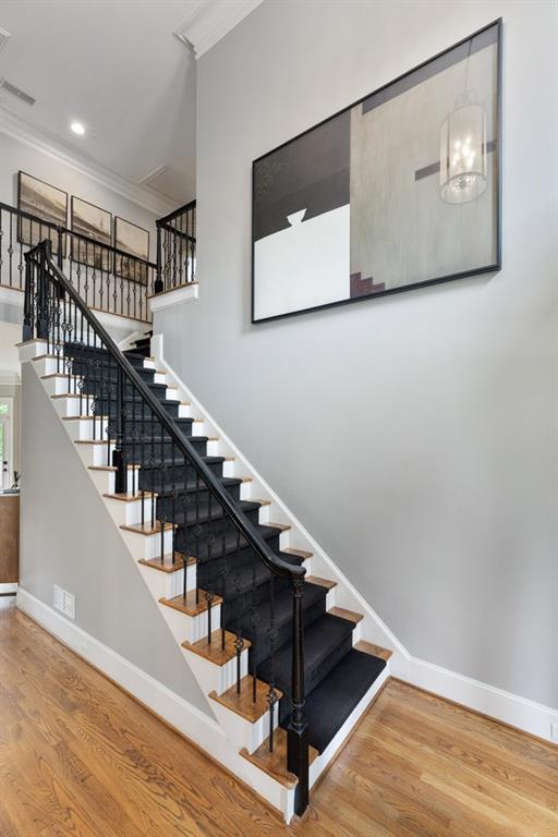 stairs featuring baseboards, ornamental molding, wood finished floors, and visible vents