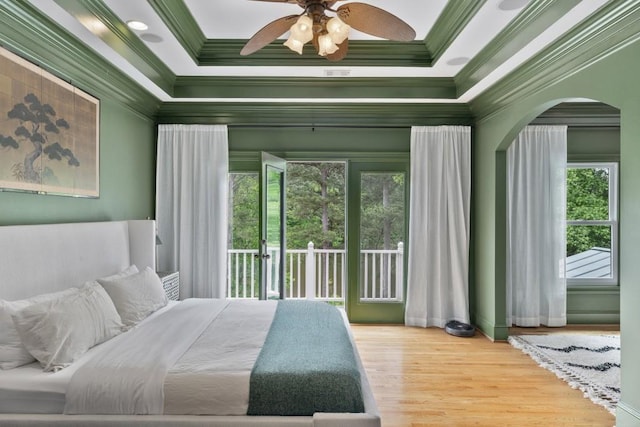 bedroom with arched walkways, ornamental molding, multiple windows, and access to exterior