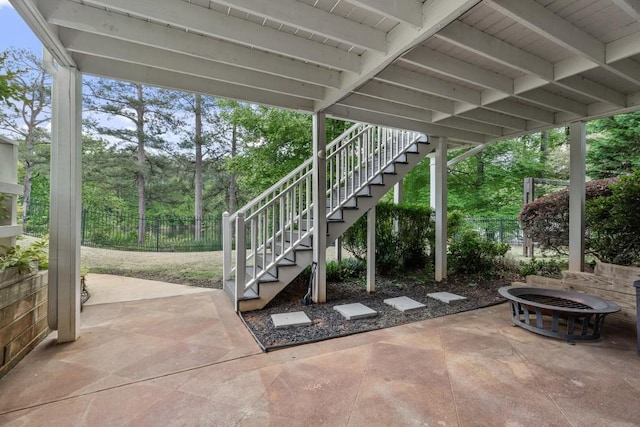 view of patio / terrace featuring fence, stairs, and a fire pit