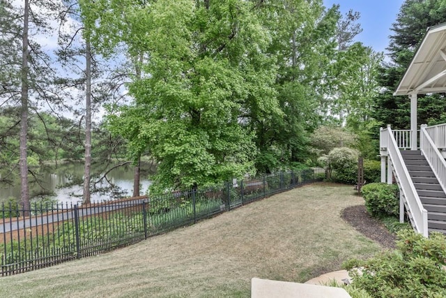view of yard with a fenced backyard, stairs, and a water view