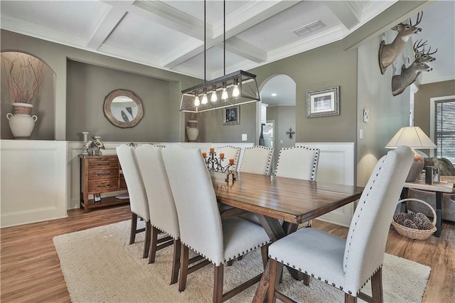 dining space featuring beam ceiling, light wood-type flooring, crown molding, and coffered ceiling