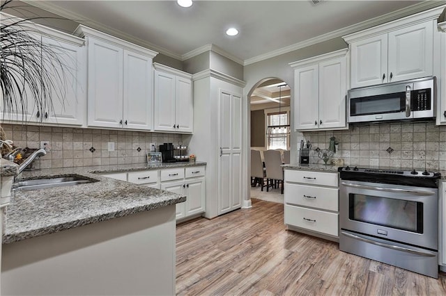 kitchen with decorative backsplash, appliances with stainless steel finishes, sink, light hardwood / wood-style flooring, and white cabinetry