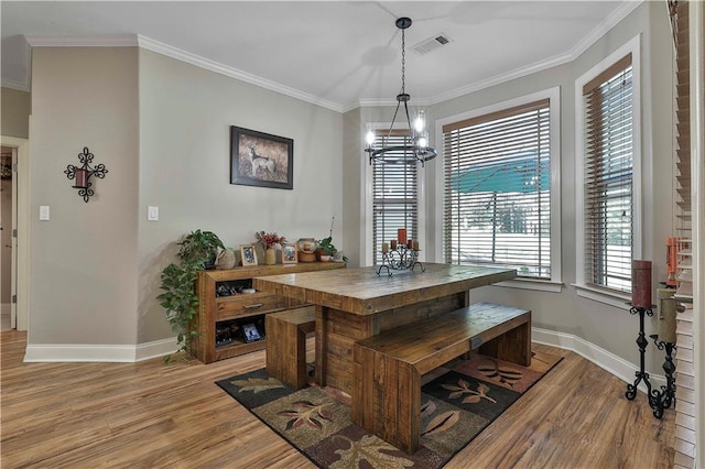 dining space with a chandelier, crown molding, and light hardwood / wood-style flooring