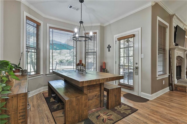 dining space featuring a fireplace, light hardwood / wood-style floors, a wealth of natural light, and crown molding