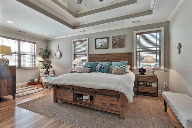 bedroom featuring a raised ceiling, ceiling fan, crown molding, and wood-type flooring