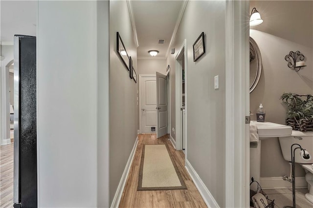 hall with crown molding and light hardwood / wood-style floors