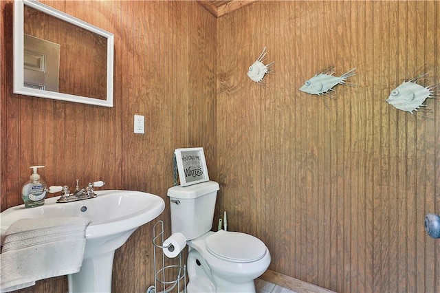 bathroom featuring wood walls, sink, and toilet