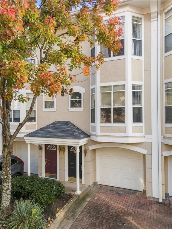 multi unit property with stucco siding, decorative driveway, and a garage