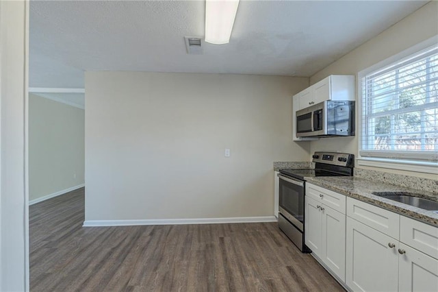 kitchen featuring appliances with stainless steel finishes, dark hardwood / wood-style flooring, light stone countertops, and white cabinets