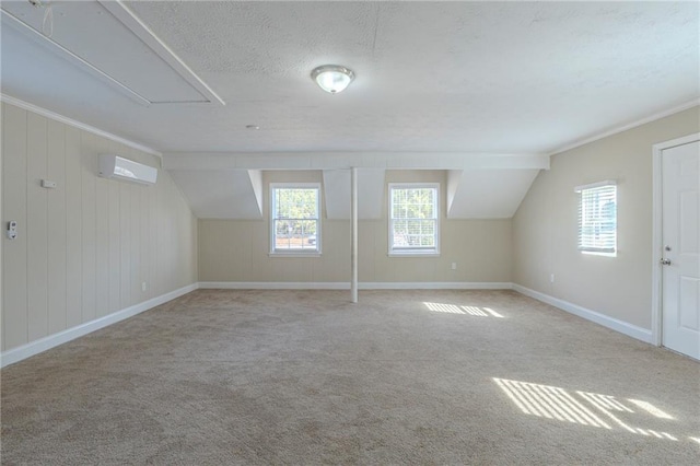 additional living space featuring a wall mounted air conditioner, vaulted ceiling, light colored carpet, and a textured ceiling