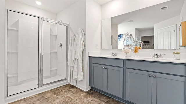 bathroom with double vanity, visible vents, a stall shower, and a sink