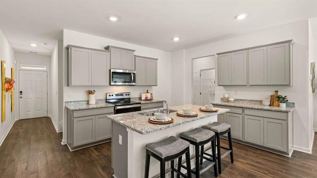 kitchen featuring appliances with stainless steel finishes, dark wood-type flooring, gray cabinetry, and a sink