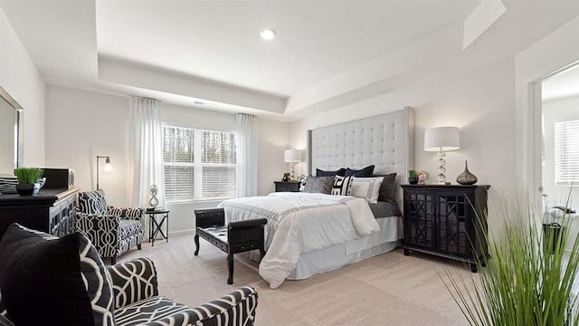 bedroom featuring a tray ceiling and light carpet