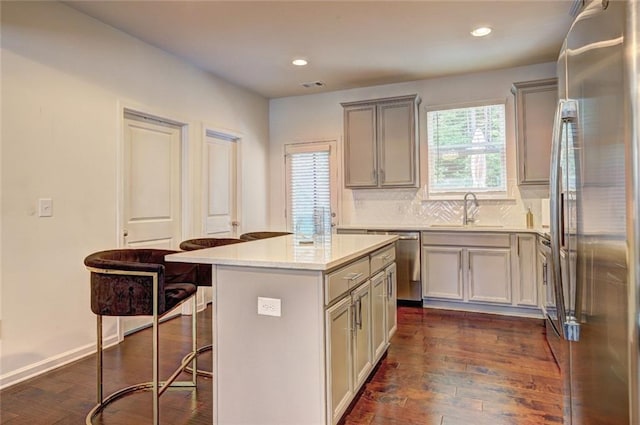 1005 Belfry Ter, Fairburn, GA 30213 - kitchen featuring appliances with stainless steel finishes, a sink, a breakfast bar, gray cabinets, and dark wood-style floors