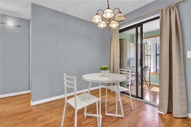 dining space with wood finished floors, baseboards, and a chandelier
