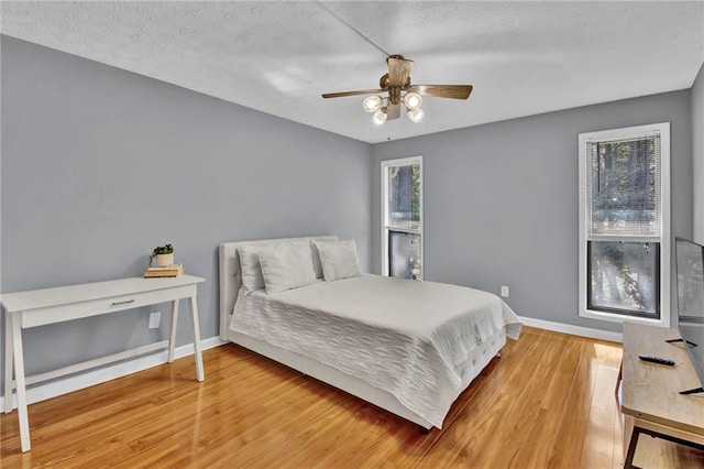 bedroom featuring baseboards, a ceiling fan, and wood finished floors
