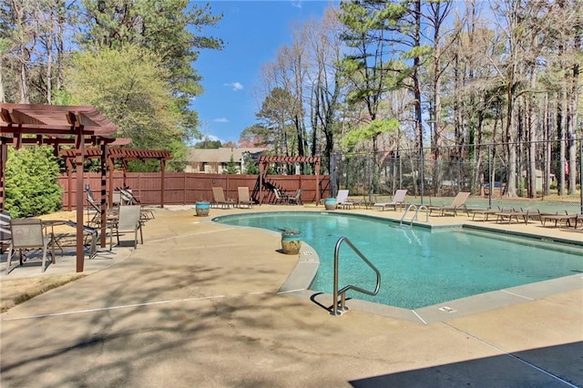 pool with fence, a pergola, and a patio
