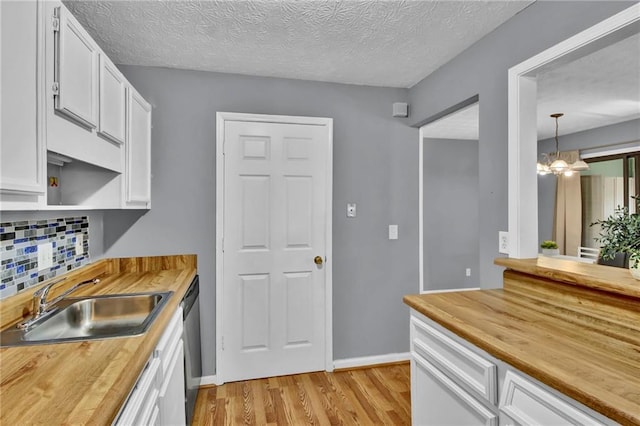 kitchen with a sink, light wood-type flooring, dishwasher, butcher block counters, and white cabinets