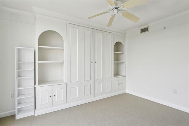 unfurnished bedroom with a closet, carpet, crown molding, a ceiling fan, and baseboards