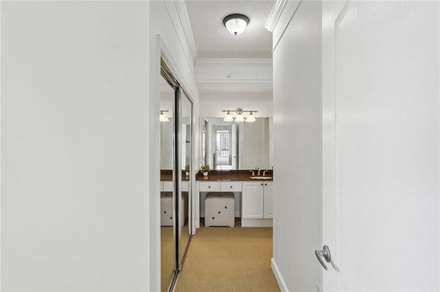 hall featuring crown molding, light carpet, and a sink