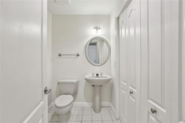 half bathroom with tile patterned flooring, toilet, and baseboards